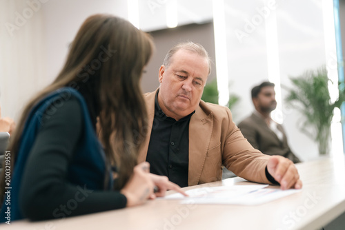 Fotografia Office meeting business discussion seated people document review indoor workplac