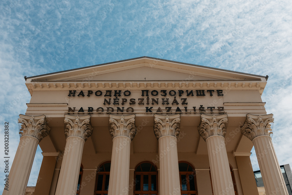 Fototapeta premium Low angle view of the National Theatre facade in Subotica, Serbia. Grand columns and historic design highlight cultural architecture.