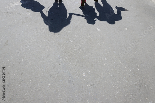 The shadow of three people on the asphalt. Silhouettes of a man, a woman, and a child.
