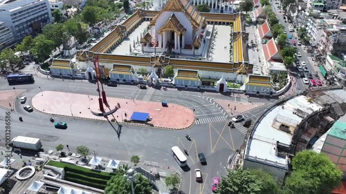 The red GiantSwing and wat suthat thepwararam temple appear within active city streets, historic architecture and movement around.
