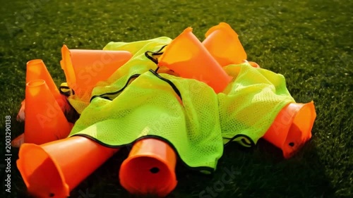 Orange Training Cones and Yellow Soccer Bibs Scattered on Green Grass Field at Sunset
