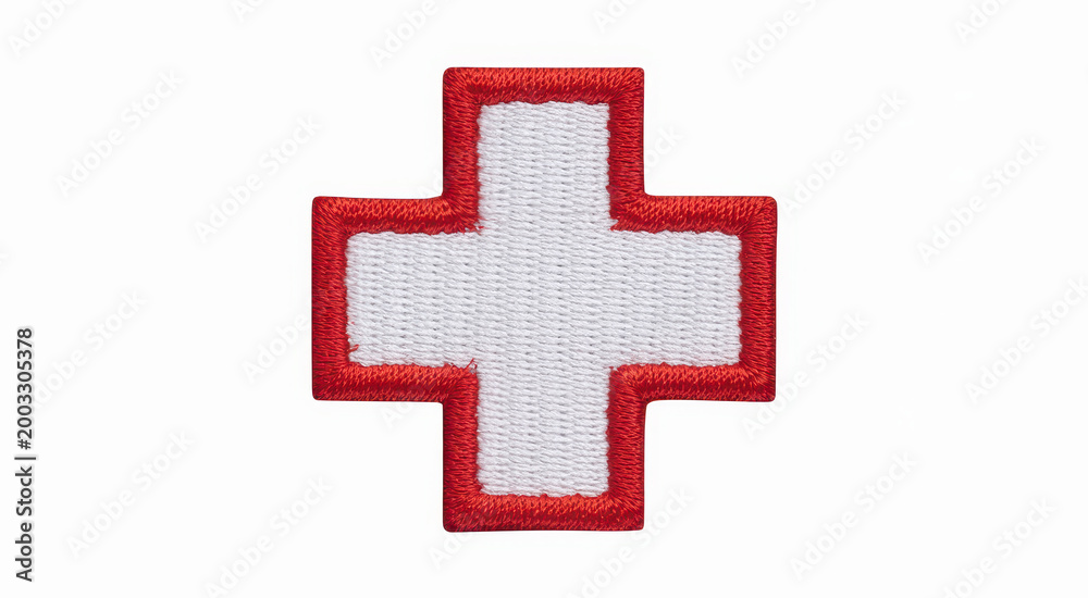 Obraz premium Embroidered red cross symbol on white fabric isolated on a plain white background surface