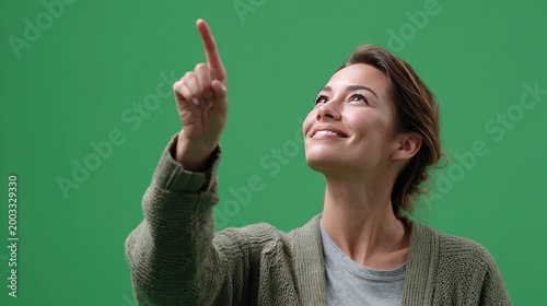 Upward Gaze with Direction: A woman gazes upwards, her finger pointing towards the sky against a vibrant green backdrop, evoking a sense of aspiration and focus.