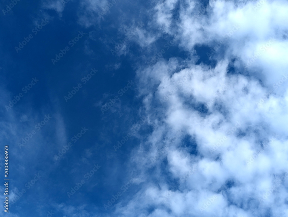 Fototapeta premium Moody white clouds across a blue black sky change in weather skyscape