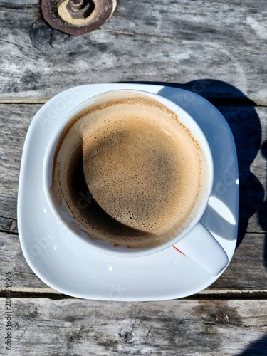 Coffee On Table. Bright Morning Scene With White Espresso Cup On Aged Wooden Surface Under Sunlight