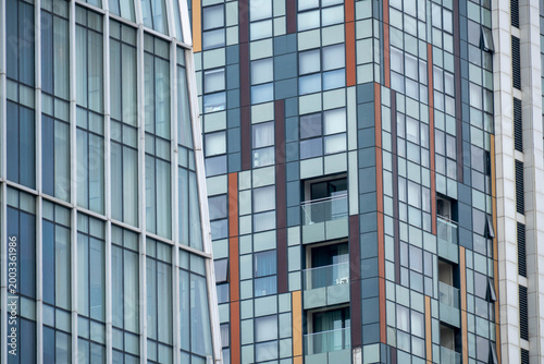 Close-up view of modern glass high-rise buildings with geometric facades, windows and balconies, showing urban architecture and abstract city patterns.