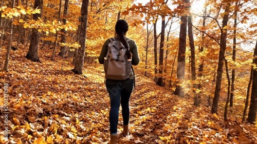 Woman walking through autumn forest trail.