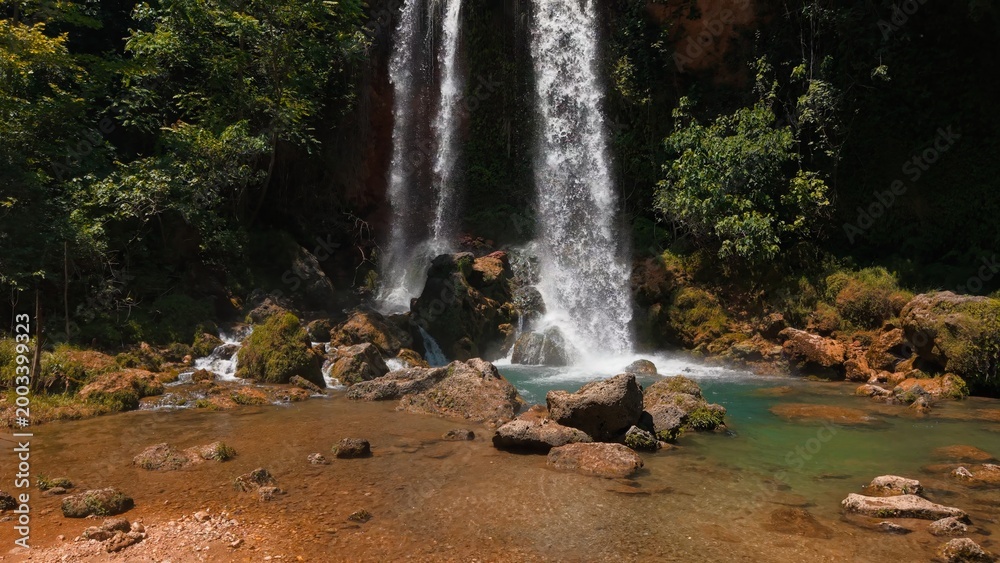 Obraz premium Waterfalls cascading down rocky cliffs, forming a tranquil stream in lush nature