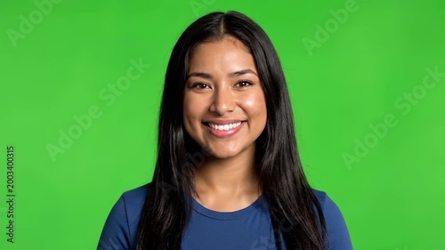 Smiling Brunette Woman: A radiant woman with flowing brunette hair and a warm smile exudes approachable confidence against a vivid green backdrop.