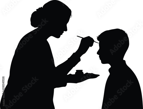 Silhouette of woman applying face paint to a child.