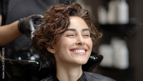Woman having her hair washed and massaged with shampoo at a hair salon, enjoying the pampering and beauty treatment