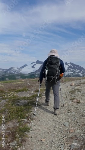 Adventurous Hiker Treks Rocky Mountain Trail Towards Majestic Snowy Peaks in British Columbia