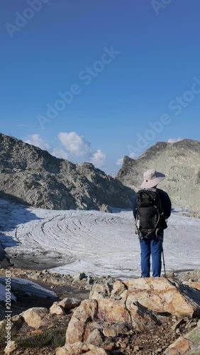 Hiker With Backpack Overlooks Majestic Glacier And Mountains In British Columbia, Canada