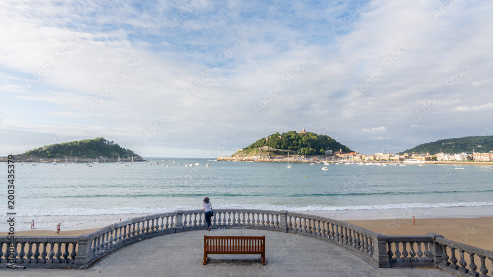 Obraz premium Woman enjoying the view of La Concha Bay in San Sebastian, Basque Country, Spain.