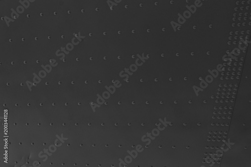 Foto Dark metal surface shows uniform pattern of evenly spaced rivets