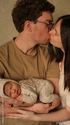 a family with a newborn baby, happy parents holding their baby in their arms, hugging and kissing