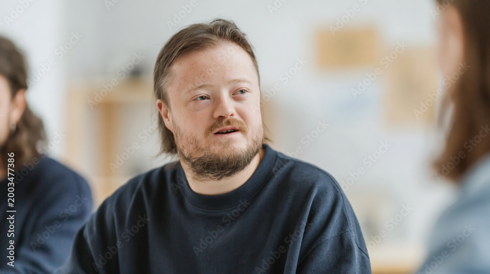 Obraz premium Close Up Portrait of a Man with Down Syndrome and Glasses Talking to Colleagues in a Modern Office Workplace Environment
