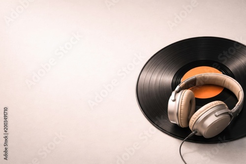 Vinyl record with headphones on light background.