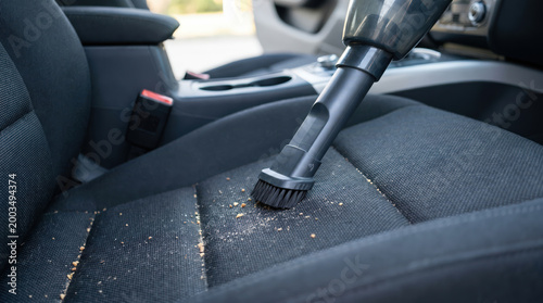 Vacuum nozzle cleaning crumbs from fabric car seat in close view highlighting auto detailing hygiene maintenance interior care service convenience or everyday cleanliness promotion concept