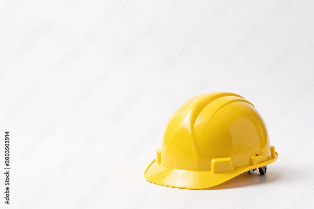 Fototapeta premium A bright yellow construction hard hat with glossy surface, reinforced ridges, brim, and adjustable strap rests on a plain white background.