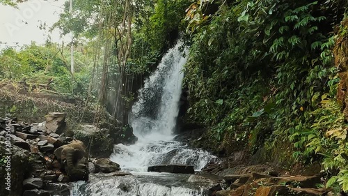 stunning waterfall in Bali surrounded by lush green jungles on a bright afternoon