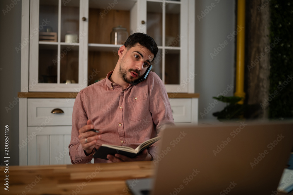 Fototapeta premium Man multitasking working from home using laptop and phone