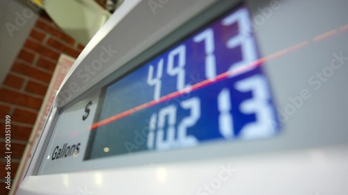 Gas station pump display showing fuel price and gallons during car gas refueling process.