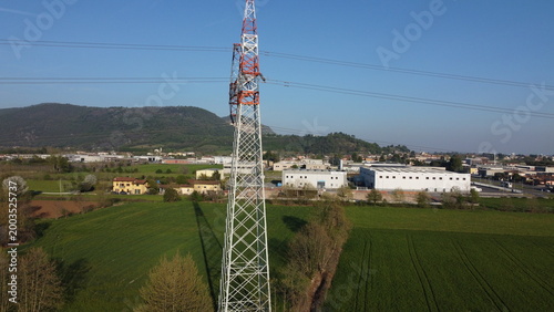 High-voltage electricity pylon in a rural landscape with industrial area