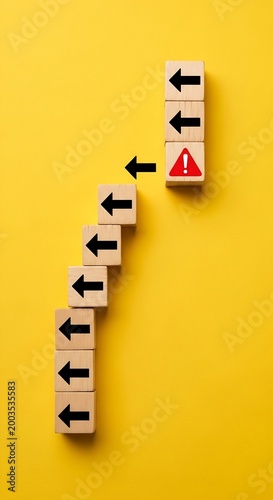 Fotografia Wooden blocks with arrows pointing to warning sign on yellow background