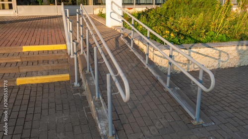 Bild auf Leinwand Inclined concrete accessibility ramp featuring gray metal safety handrails stand