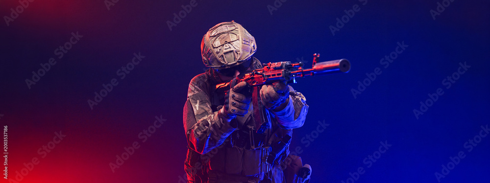 Fototapeta premium Soldier in combat gear on abstract red and blue blurred backdrop. Concept readiness and discipline. 