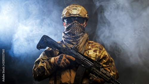 Bild auf Leinwand Armed soldier in combat uniform holding weapon on black background with smoke