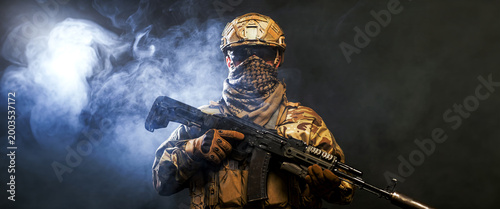 Bild auf Leinwand Military soldier with assault rifle standing on dark smoky background