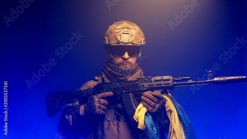 Photos Male soldier in tactical uniform with assault rifle, isolated on blue-black gradient background