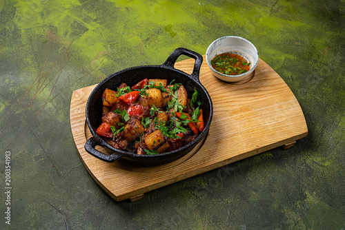 Foto Roasted vegetables with meat in cast iron pan served with fresh herbs and sauce