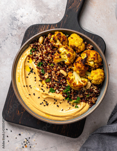 Top down view of a colorful grain bowl topped with leftover roasted cauliflower, seeds, and creamy tahini dressing.