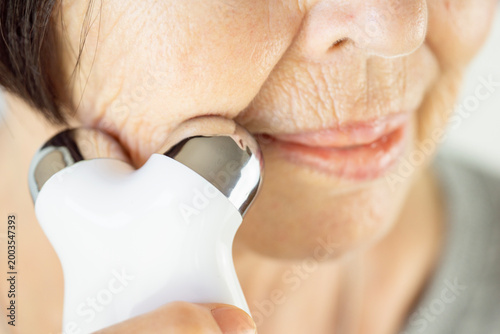 Fotografie biohacking facial rejuvenation senior woman using microcurrent device for skin l