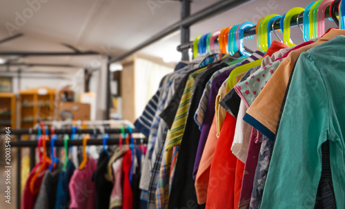 Colorful children's clothes hanging on a rack at a sustainable swap event. Various jackets, sweaters, and shirts in bright colors symbolize reuse, recycling, and eco-friendly fashion for kids.