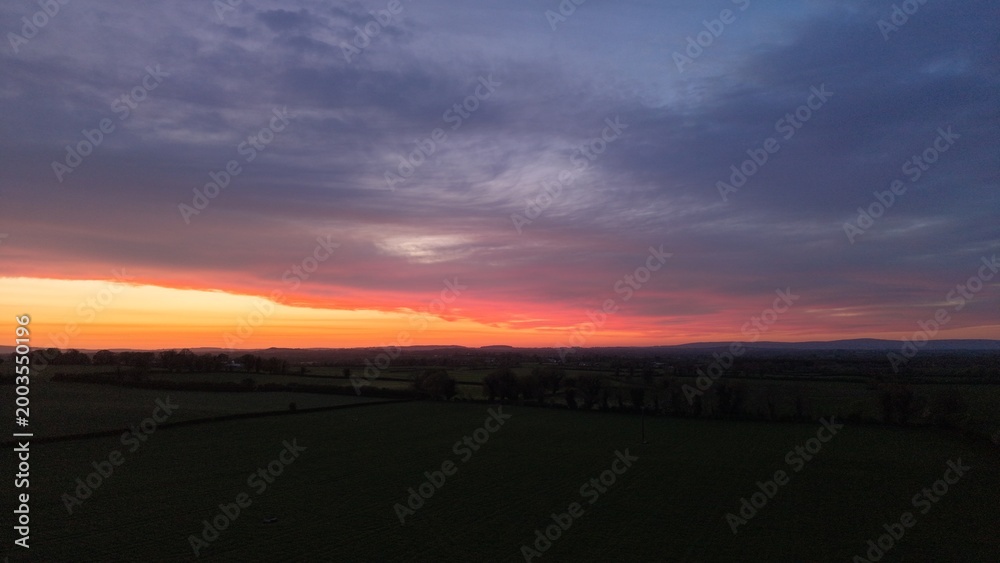 Fototapeta premium Colorful sunset horizon over dark rural landscape silhouette