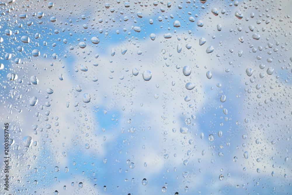 Obraz premium Window with water drops. View on blue sky with clouds through wet glass