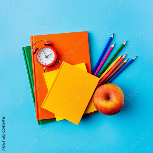 Bright and Colorful School Supplies Arranged on Blue Background With an Apple...