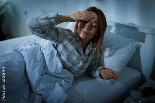 Tableau sur toile Woman with headache in bed at night