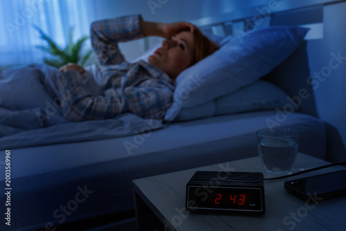 Woman wakes up in the middle of the night in dark bedroom