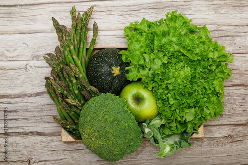Top View of Green Vegetables and Apple in Wooden Crate on Wood Background