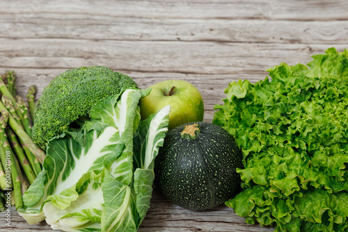Fresh Green Vegetables and Apple Assortment on Rustic Wooden Background