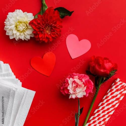 Colorful Arrangement of Flowers and Paper Hearts on Red Background for Celebr...