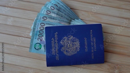 Armenian passport with banknotes on table in slow motion