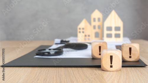 Wooden blocks with exclamation mark and blurred house models.