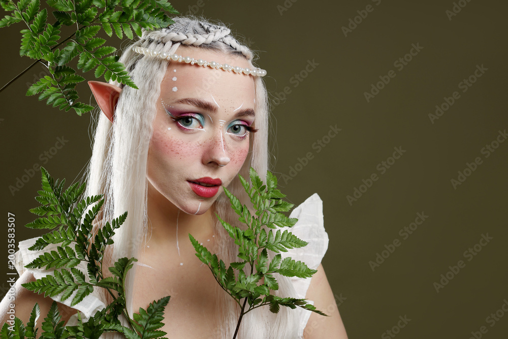 Fototapeta premium Beautiful elf girl with floral decor on dark olive background, space for text