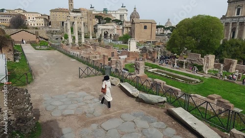 Fashion skylish female model walk visiting ancient Roman Forum in Rome, Italy, aerial drone view